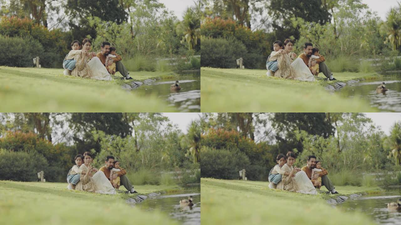 双胞胎小孩和妈妈和爸爸坐在湖边玩耍。