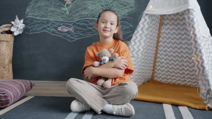 迷人的儿童拥抱毛绒玩具的肖像在家里微笑着看着相机