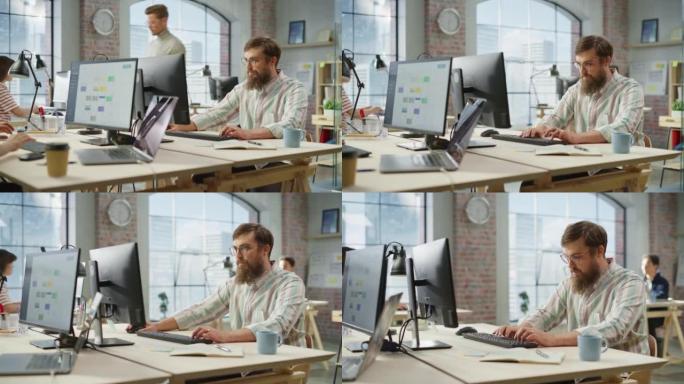 在明亮宽敞的办公室中使用计算机时，戴着眼镜的有创意的大胡子白人的肖像微笑。男团队经理向同事提供反馈。