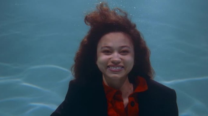 处理工作中的压力。在水下的电影肖像下，年轻快乐的女商人对镜头慢动作微笑。