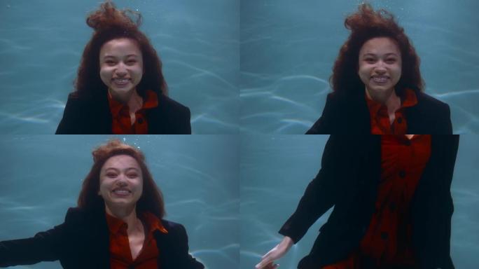 处理工作中的压力。在水下的电影肖像下，年轻快乐的女商人对镜头慢动作微笑。