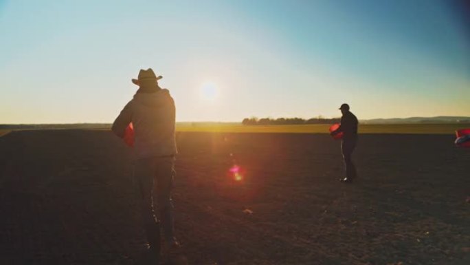 三名农民在日落时分播种田地