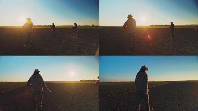 三名农民在日落时分播种田地
