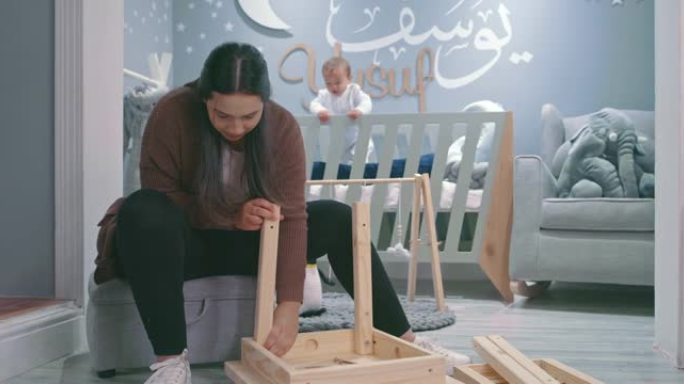 4k视频片段，一名年轻女子在家里的婴儿托儿所从事木制项目
