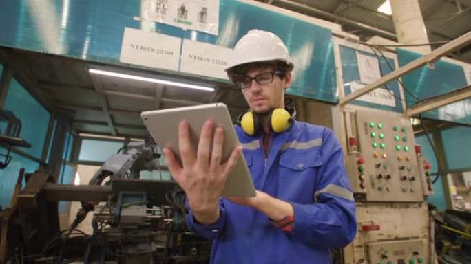 在制造业中使用数字平板检查和控制自动化机器人手臂机的专业工业工程师的轨道拍摄肖像。人和技术或创新概念