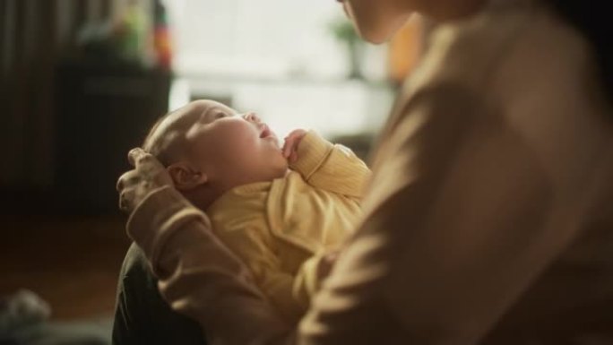 一个可爱的亚洲婴儿在母亲的腿上休息的肖像，当她对她说话时。活跃的小孩咕咕叫，试图交流，用充满爱和感情