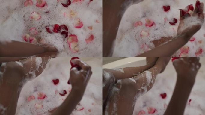非洲裔美国美女用泡沫和玫瑰花瓣洗澡的手