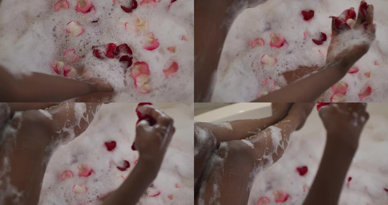 非洲裔美国美女用泡沫和玫瑰花瓣洗澡的手