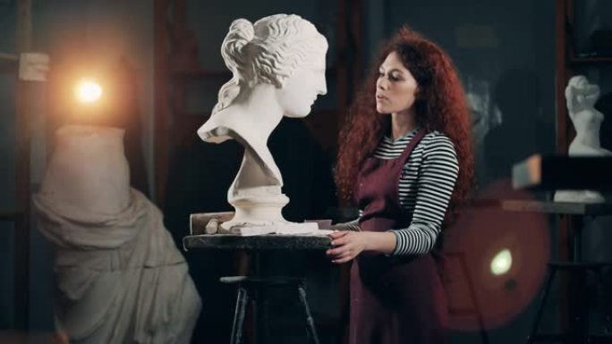 雕塑家女士正在照顾一件白色石膏半身像。灵感，创造性的工作理念。