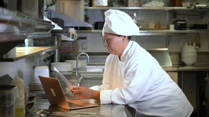 使用笔记本电脑的商用厨房女厨师