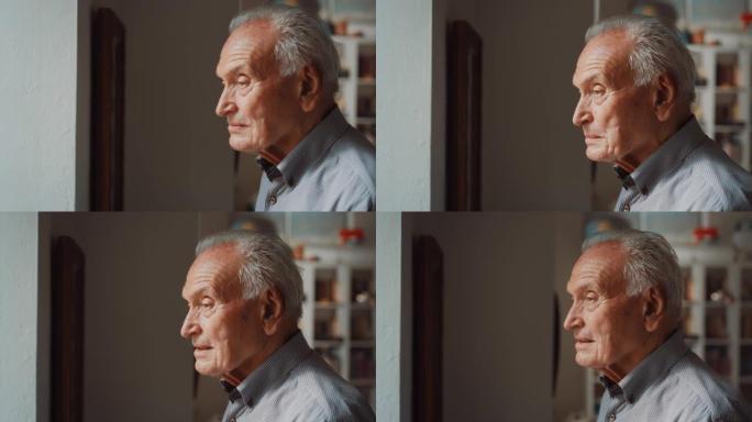 家里一个老人的肖像靠近窗户，透过窗户看。一位老人看着他的家人来探望他。他很开心，感觉怀旧