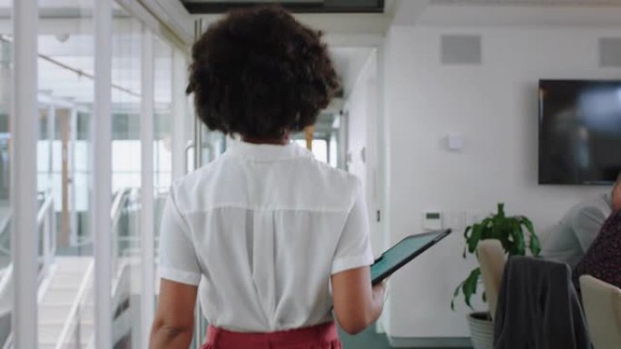 后视图混合种族商业女性走过办公室拿着平板电脑在企业工作场所的成功职业生涯4k