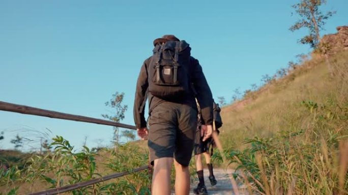 周末与朋友在日出时在山顶上行走的男性徒步旅行者。