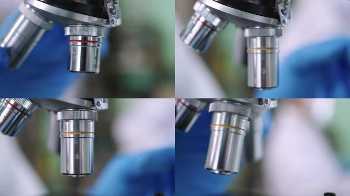 在实验室显微镜下使用样品的科学家的手的特写。