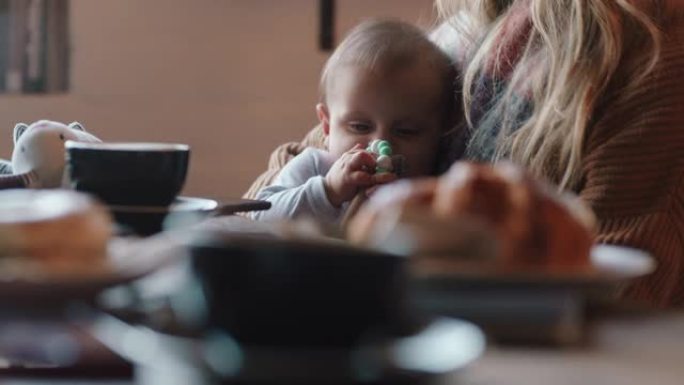 年轻的母亲在咖啡馆里照顾婴儿，使用奶嘴养育孩子在繁忙的餐厅里放松，享受母亲的生活