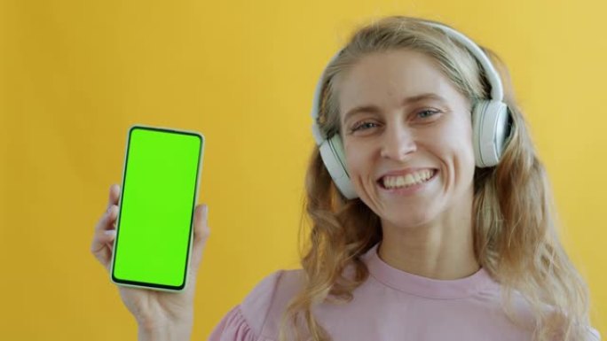 戴着绿屏色度键智能手机耳机的女孩肖像