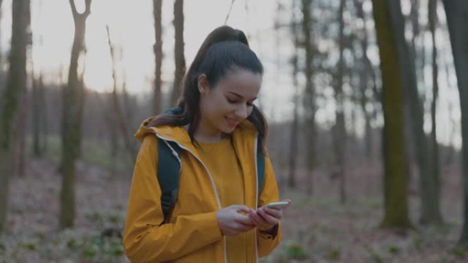 女人在森林徒步旅行时使用手机