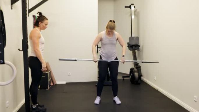 私人教练指导女性进行杠铃锻炼
