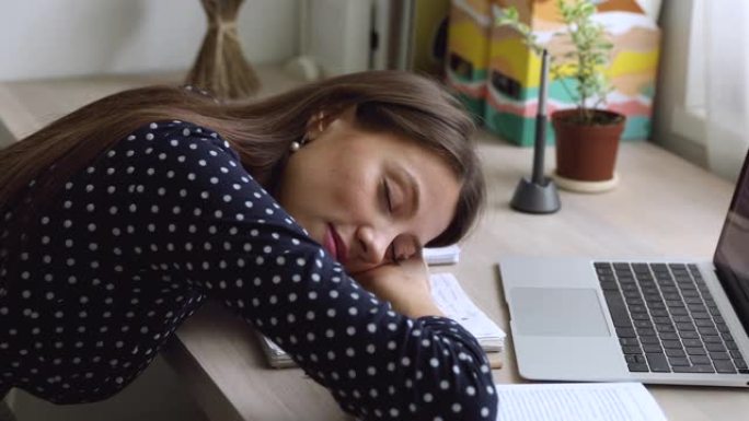 特写过度劳累的学生女孩在办公桌前睡着了