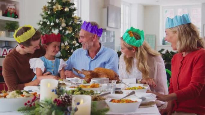 饭前戴纸帽在家庆祝圣诞节的多代家庭肖像