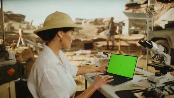 考古挖掘地点: 女性考古学家使用绿屏色键显示笔记本电脑，分析化石遗迹，古代文明文化文物。历史学家在挖