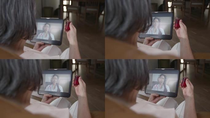 年迈的祖母拿着一瓶药咨询医生，用平板电脑作为视频通话，以缩小他们之间的距离，减少传播感染的机会