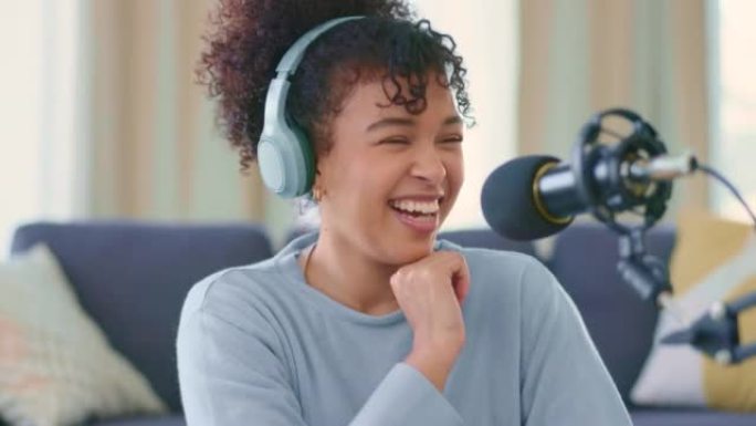 开朗的女人戴着耳机录制播客，并在脱口秀节目中通过麦克风交谈。有趣的非洲博客作者使用音频设备并在家中进