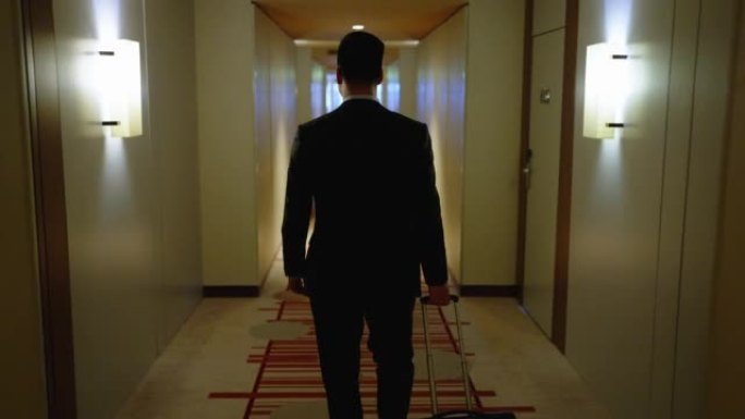 穿着商务服装的男人的后视图，带着包走向他的酒店房间