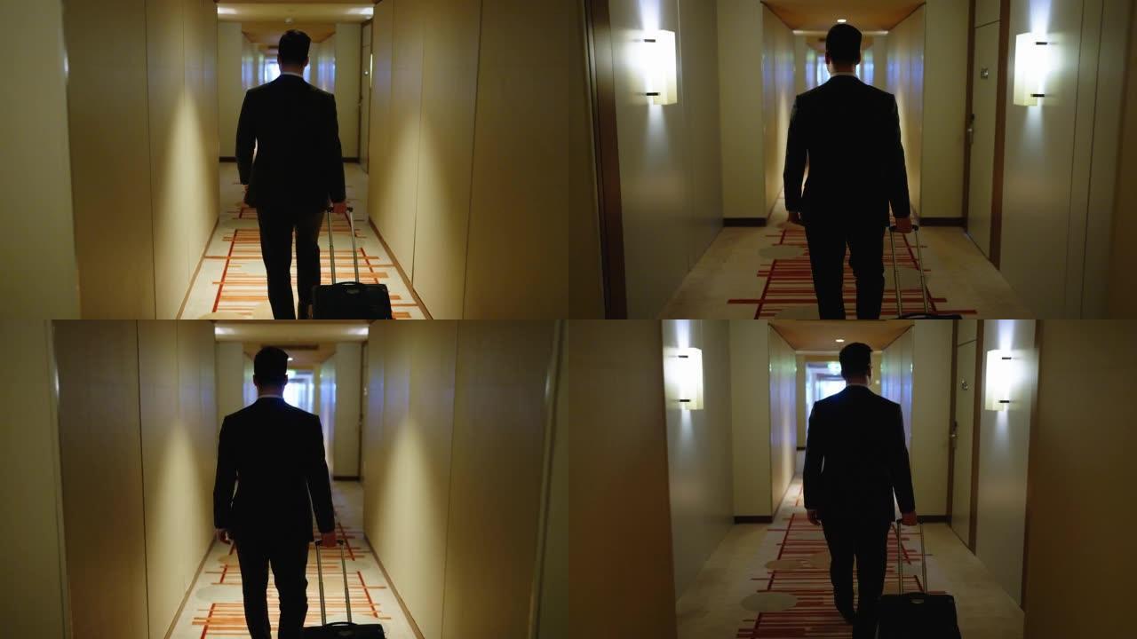穿着商务服装的男人的后视图，带着包走向他的酒店房间