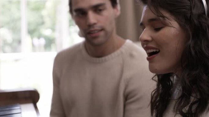 一对年轻夫妇在家里唱圣诞颂歌时弹钢琴的4k视频片段