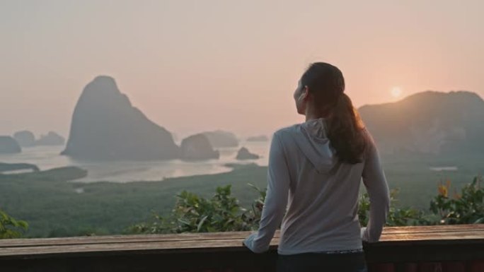 亚洲体育女子站在山顶，在日落时欣赏壮丽的景色