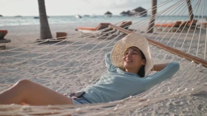 游客在热带岛屿海滩的吊床上放松。暑假
