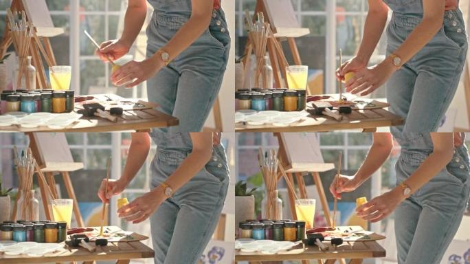 一位女画家在画室为绘画在调色板上涂漆的特写镜头。艺术家在车间工作时使用画笔混合颜色。女人为画布上的艺