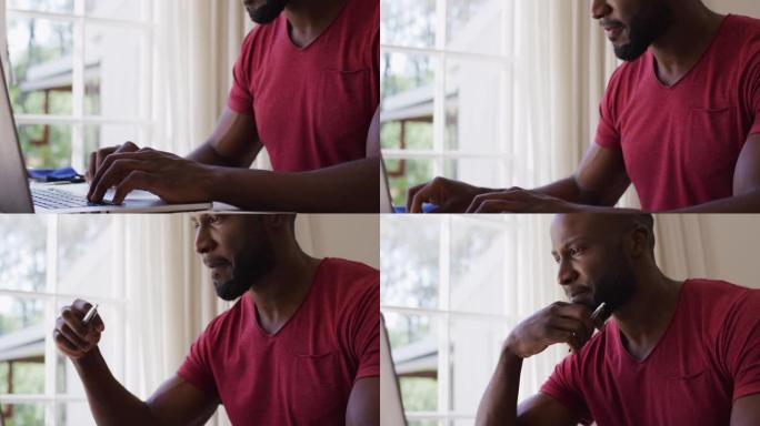 非裔美国人坐在家里的桌子上，用笔记本电脑拿着笔