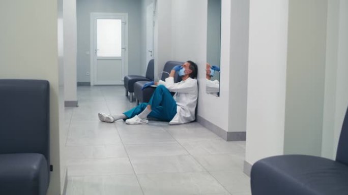 大流行期间，压力很大的中年医生在诊所走廊休息