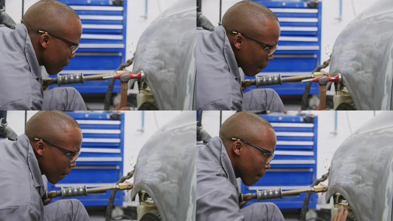 非裔美国男汽车修理工手持螺丝刀用锤子修车