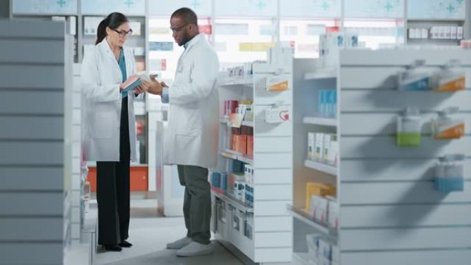 药房: 黑人男性和白人女性药剂师使用数字平板电脑谈论药物，药物，维生素，补充剂，疫苗，保健品。药店的