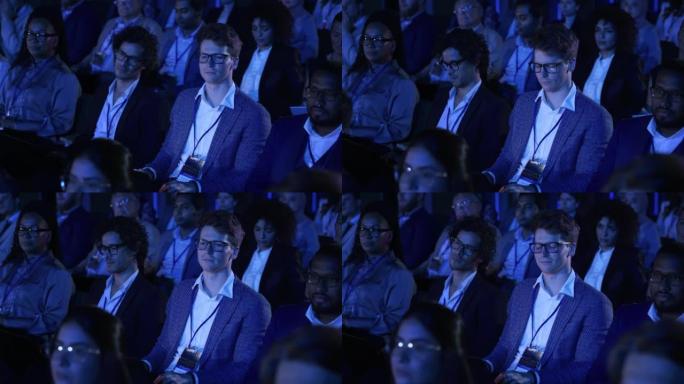 Male Sitting in a Dark Crowded Auditorium at an In