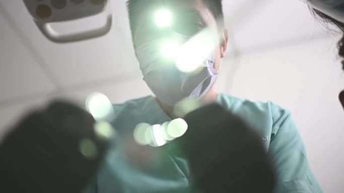 亚洲中国男性牙医牙髓病专家，戴着放大镜，从上方看光线