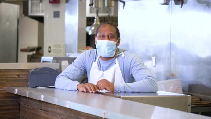 在自助餐厅工作的非裔美国人戴着口罩