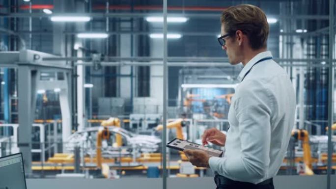 穿着眼镜和白衬衫的英俊工程师使用平板电脑，在汽车装配厂的办公室里望去。在技术设施中从事车辆设计的工业