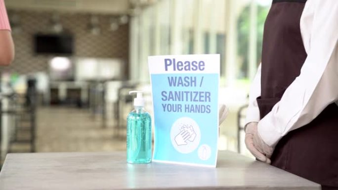 4K UHD: 亚洲有吸引力的女服务员的特写镜头将酒精凝胶洗手液推向顾客，然后再进入，以减少冠状病毒