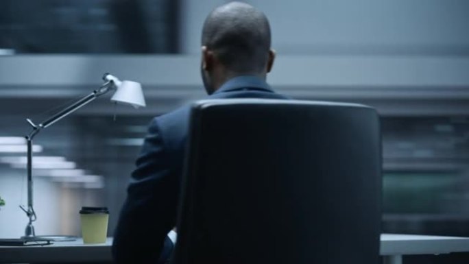 360学位办公室: 英俊成功的黑人商人坐在办公桌前使用笔记本电脑。穿着西装从事股市投资的非裔美国企业