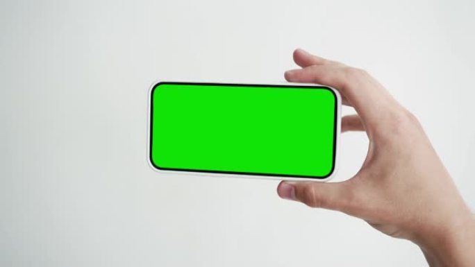 带有绿色色度键特写的年轻人触摸屏智能手机。在手机模型POV上敲击手势。概念观看和展示互联网社交媒体，