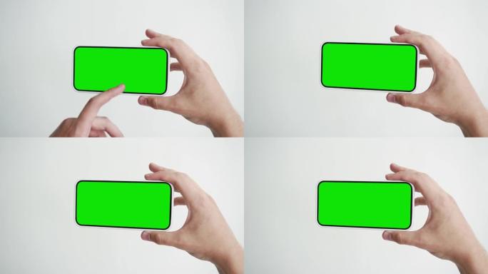 带有绿色色度键特写的年轻人触摸屏智能手机。在手机模型POV上敲击手势。概念观看和展示互联网社交媒体，