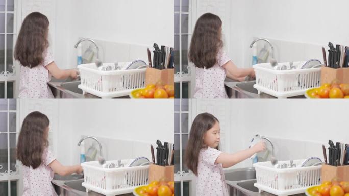 亚洲小女孩在帮妈妈做家务，在厨房洗碗