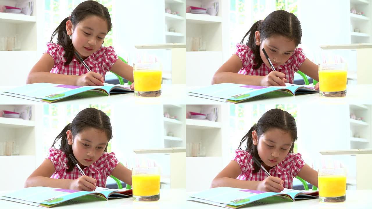 年轻的亚洲女孩坐在桌旁做作业