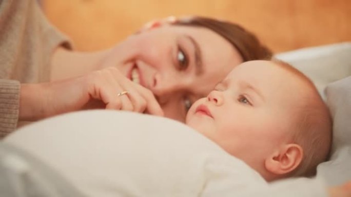 一个快乐的母亲和一个可爱的新生婴儿玩耍的特写镜头。妈妈和一个蹒跚学步的孩子在一起，轻轻地抚摸女孩的脸