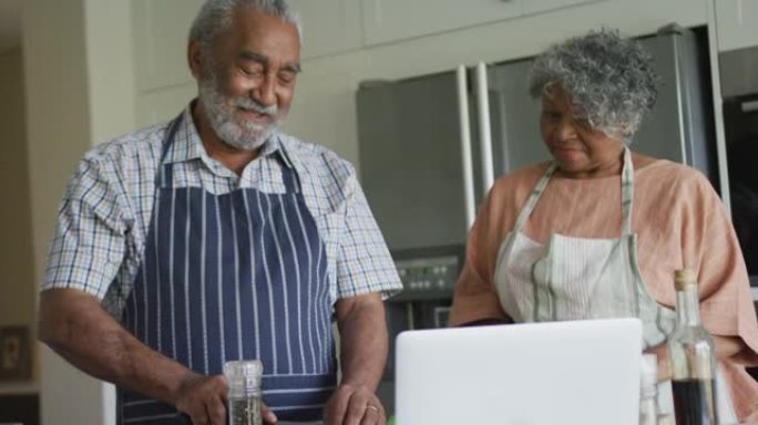 快乐的非洲裔美国老年夫妇一起做饭的动画，使用笔记本电脑