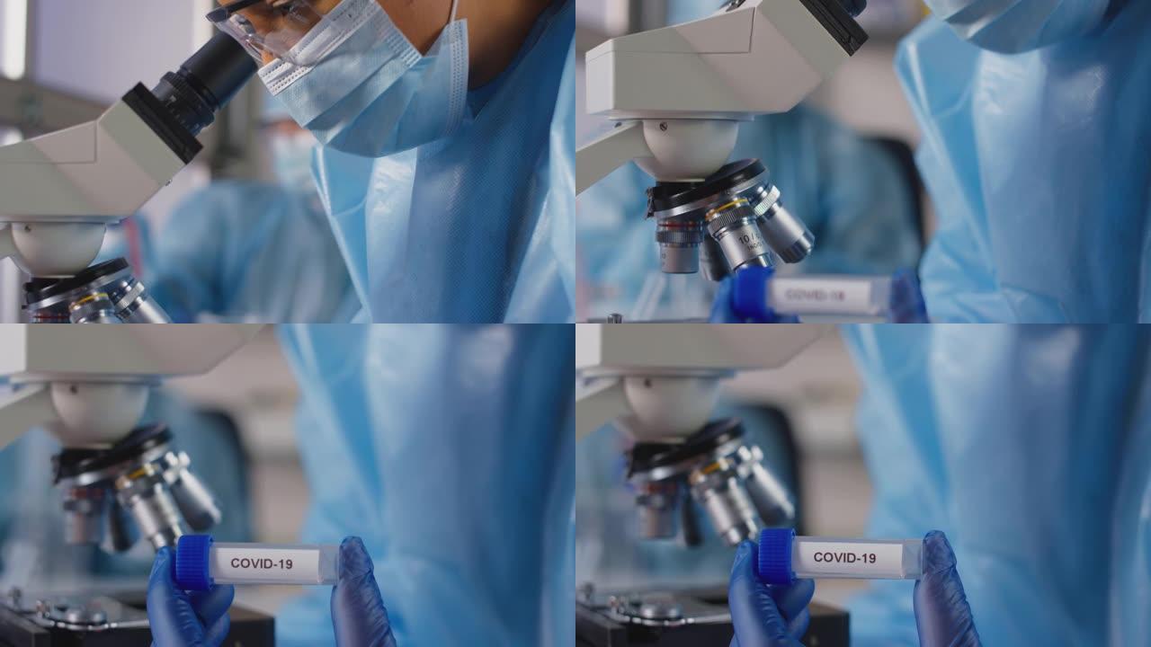 实验室女工作人员穿着个人防护用品，拿着标记为Covid-19的试管，分析样本